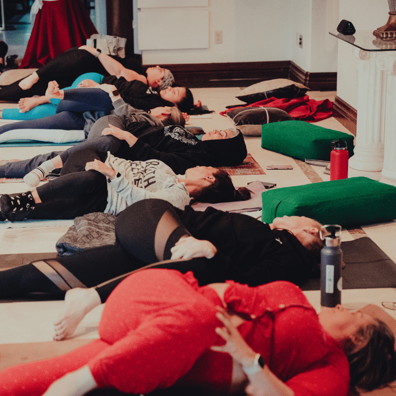 A group of women lying on their yoga mats in a twist