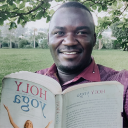 Image of a Black man smiling and holding a "Holy Yoga" book.